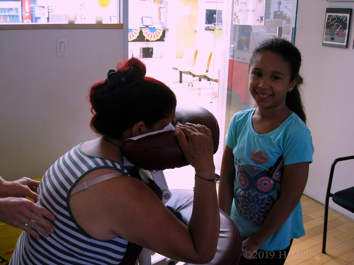 Watching Her Mom Get Chair Massage, This Flat Rate Kid Looks On